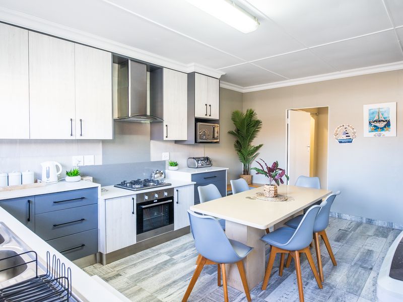 Modern open-plan kitchen and dining area featuring contemporary two-tone cabinetry, integrated appliances, and durable wood-look laminate flooring.
