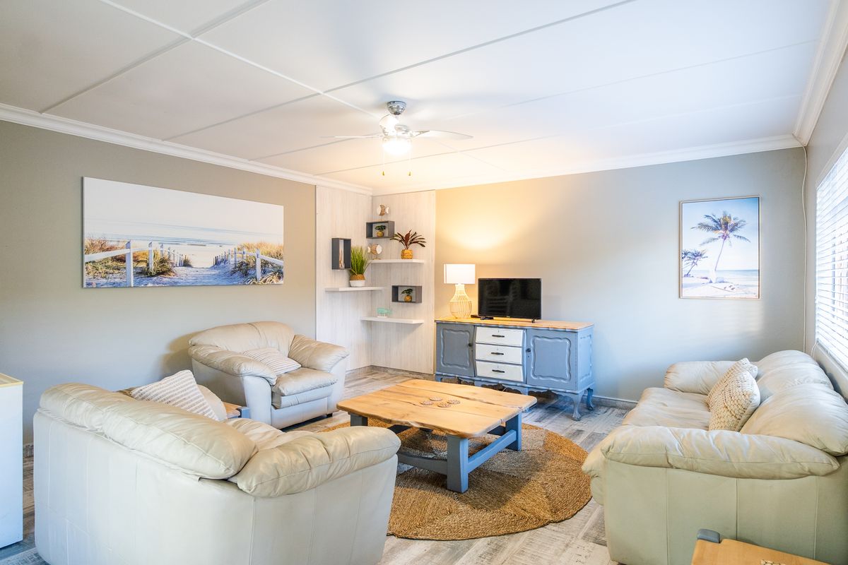 A comfortable living room featuring tiled flooring, a ceiling fan, and built-in shelving, creating a bright and inviting space.