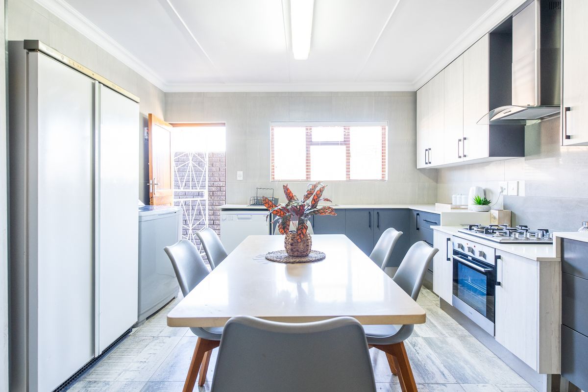 Modern kitchen featuring sleek cabinetry, built-in gas hob, electric oven, extractor fan, and tiled finishes with direct access to an outdoor area.