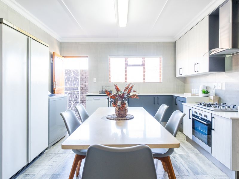 Modern kitchen featuring sleek cabinetry, built-in gas hob, electric oven, extractor fan, and tiled finishes with direct access to an outdoor area.