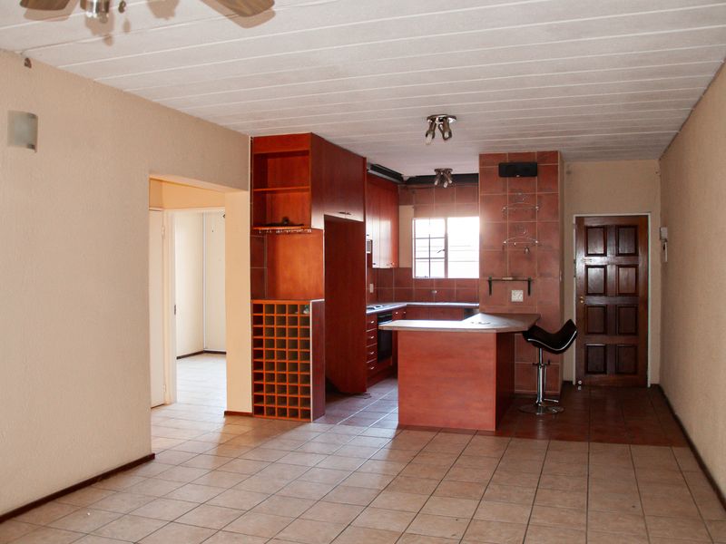 Open plan kitchen and living area featuring built-in wooden cabinetry, a breakfast counter, wine rack, and tiled flooring throughout.