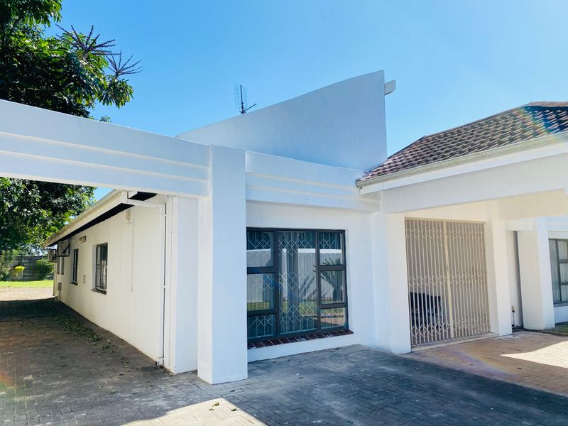Front elevation of a well-maintained house featuring a paved driveway, secure gated entrance, and modern aluminium window frames under a tiled roof.