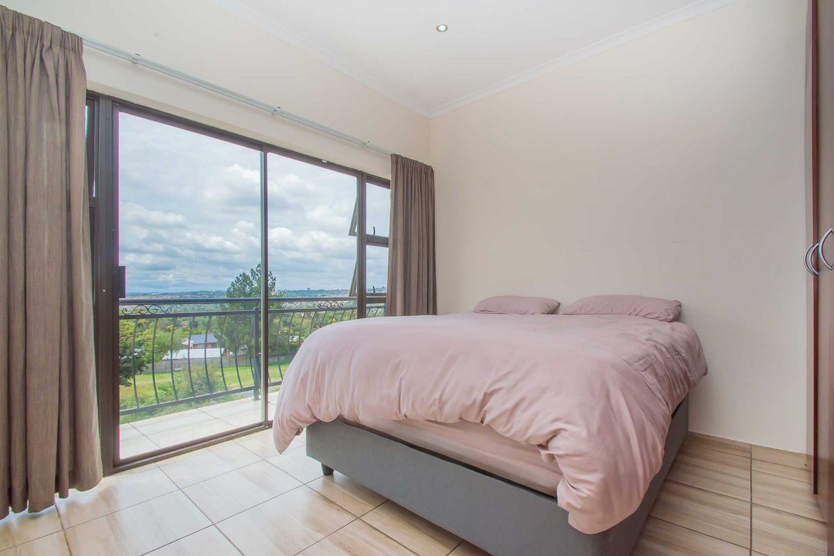 A bright bedroom featuring large sliding glass doors that open onto a private balcony with scenic views.