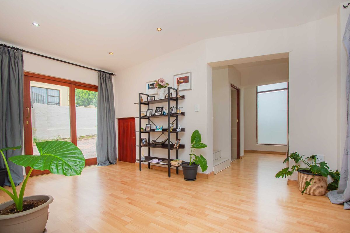 A bright living area featuring light wood laminate flooring, recessed ceiling lighting, and sliding glass doors providing access to the outdoor patio.