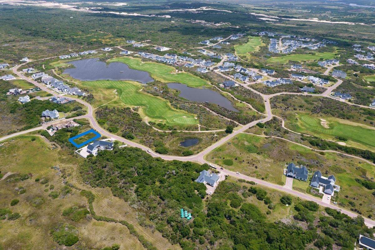 Aerial view of a vacant residential plot located within a scenic golf estate, surrounded by natural landscape and established residential properties.