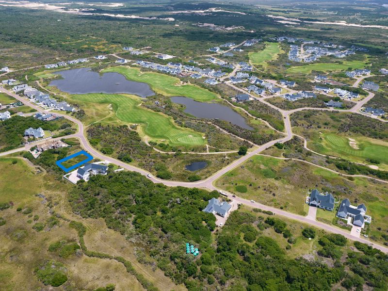 Aerial view of a vacant residential plot located within a scenic golf estate, surrounded by natural landscape and established residential properties.