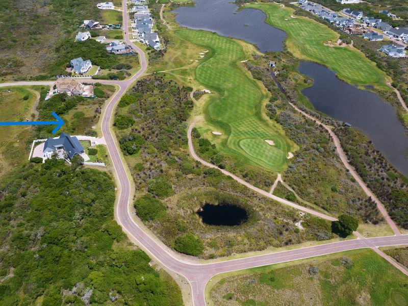 Aerial view of a residential vacant land plot situated within a golf estate, featuring surrounding natural landscape and proximity to golf course fairways.