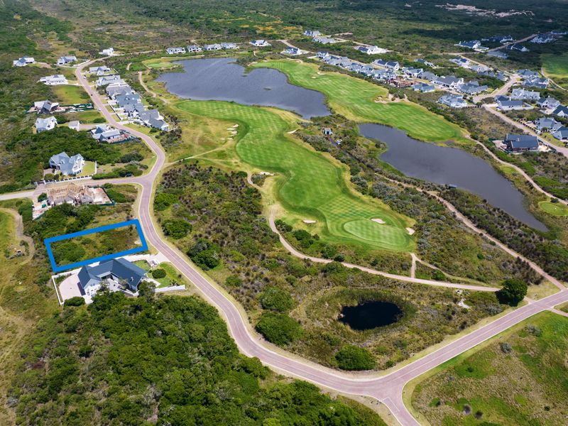 Aerial view of a vacant residential plot situated within a scenic golf estate, surrounded by natural landscape and water features.