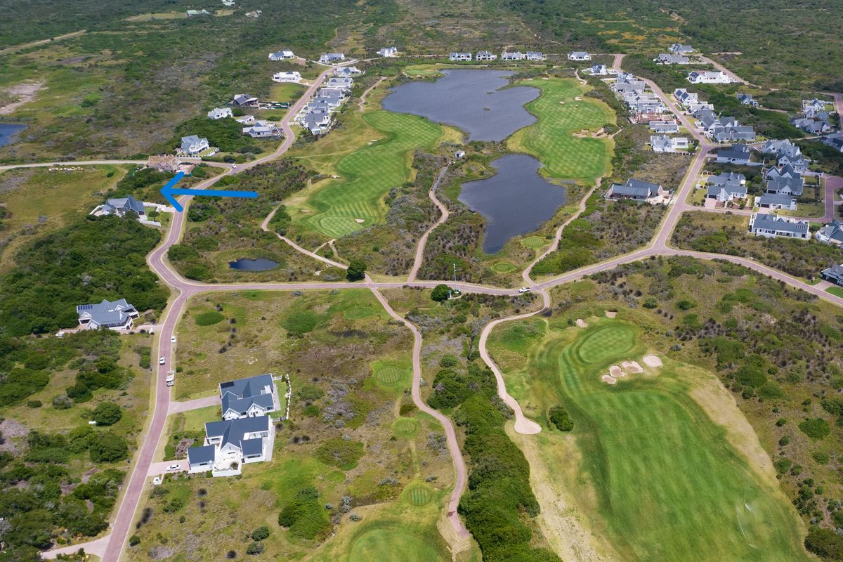 Aerial view of a residential estate featuring a golf course, natural landscape, and surrounding residential properties.