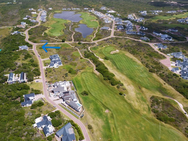 Aerial view of a vacant residential plot situated within a scenic golf estate, featuring established infrastructure and surrounding natural landscape.