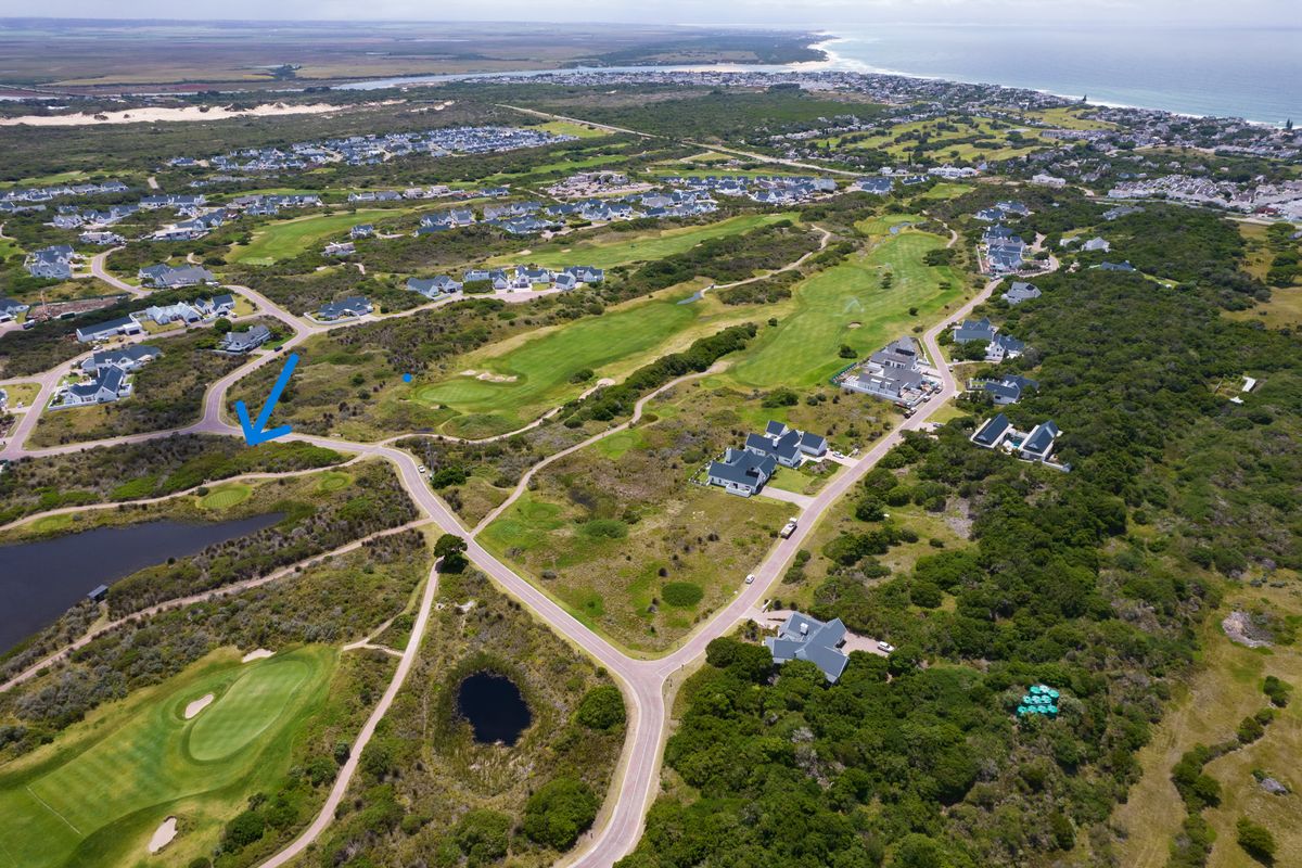 Aerial view of a residential estate featuring golf course fairways, natural coastal vegetation, and proximity to the ocean.