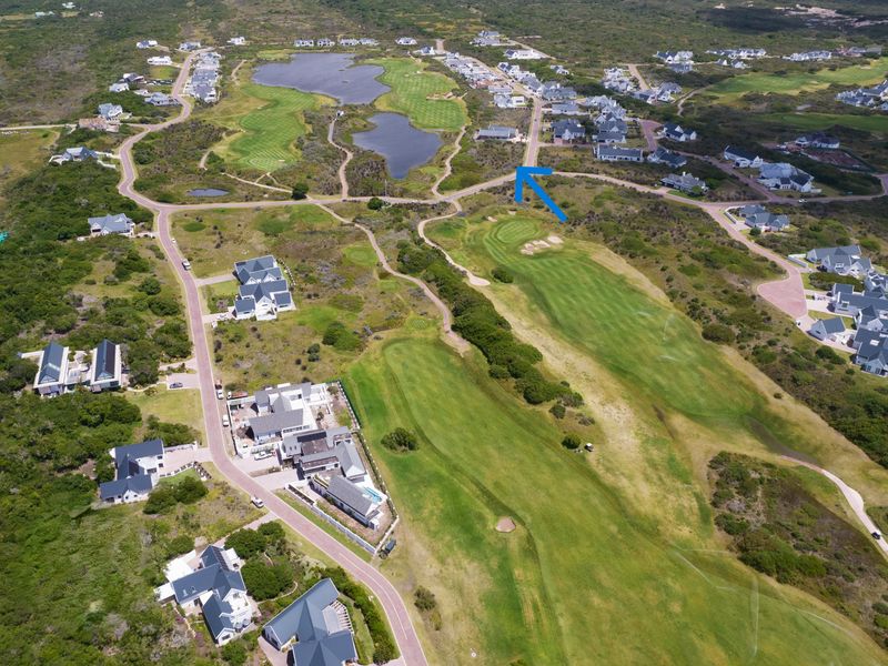 Aerial view of a residential golf estate showing the surrounding landscape, fairways, and road network with a blue arrow indicating the property location.