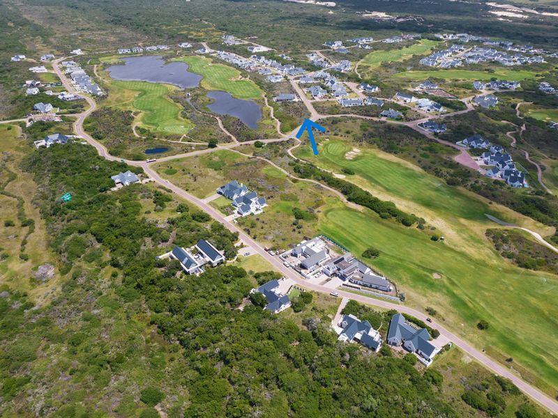 Aerial view of a residential estate featuring paved roads, surrounding natural landscape, and an adjacent golf course.