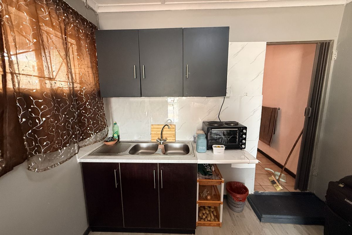 Compact kitchen area featuring dark cabinetry, a double stainless steel sink, and tiled splashback, providing a functional workspace.