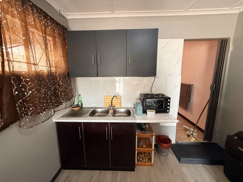 Compact kitchen area featuring dark cabinetry, a double stainless steel sink, and tiled splashback, providing a functional workspace.