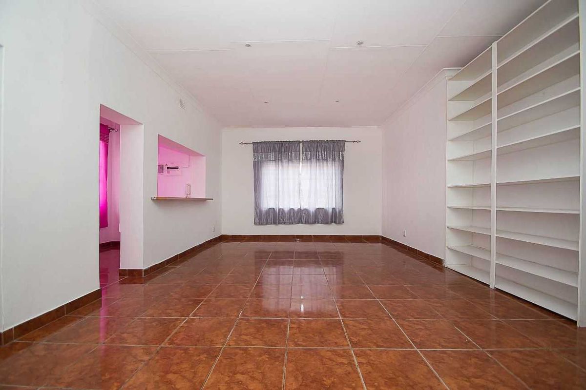 Spacious living area featuring tiled flooring, built-in shelving, and a convenient serving hatch connecting to the adjacent room.