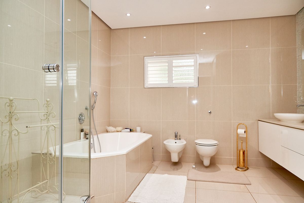 Modern bathroom featuring a built-in bathtub, glass-enclosed shower, wall-mounted toilet and bidet, and a sleek floating vanity with a vessel sink.