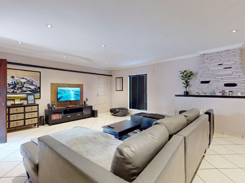 Spacious living room featuring tiled flooring, recessed downlights, and a prominent decorative stone fireplace, offering a comfortable and functional layout.