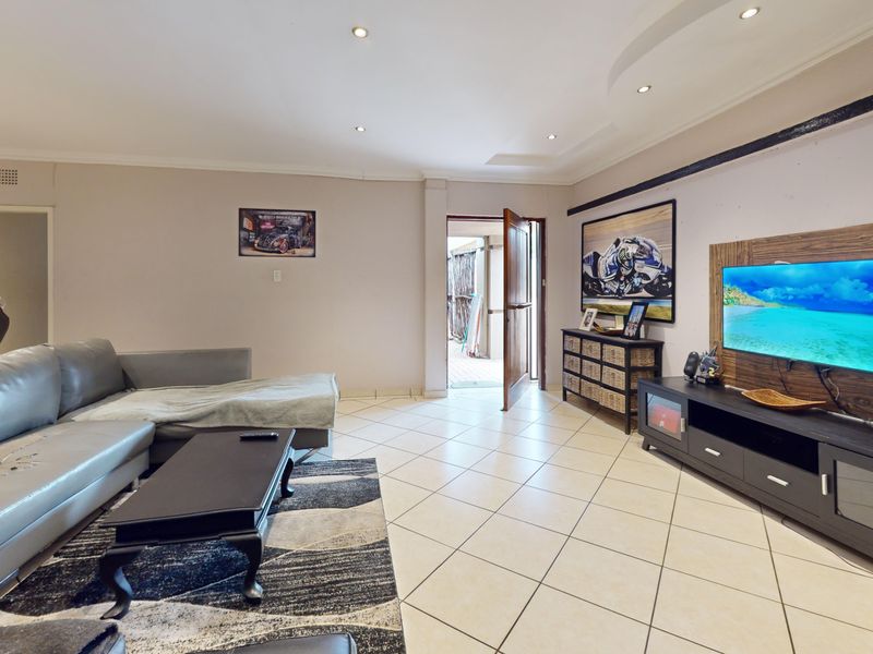 Spacious living room featuring tiled flooring, recessed downlighting, and a feature wall panel, providing a functional and open living area.
