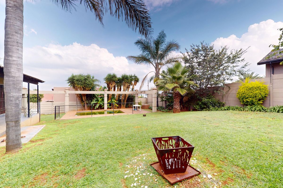 Spacious rear garden featuring a swimming pool with safety fencing, a covered patio area, and established landscaping.