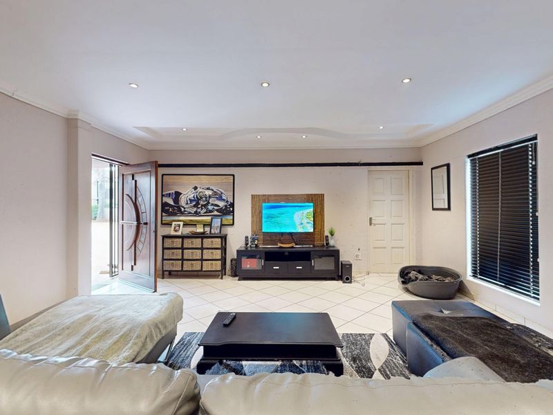 A spacious living room featuring tiled flooring, recessed ceiling lighting, and a coved ceiling, providing a neutral foundation for interior design.