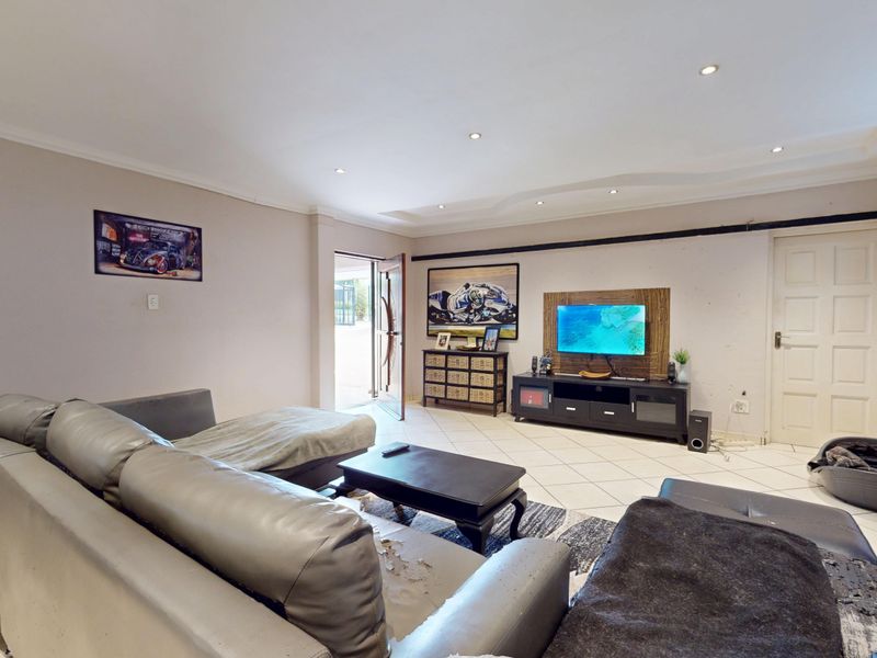 A spacious living room featuring tiled flooring, recessed downlighting, and a coved ceiling, providing a functional base for comfortable family living.