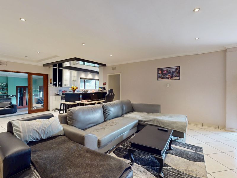 Spacious open-plan living area featuring tiled floors, recessed lighting, and a functional kitchen island, with seamless access to outdoor patio spaces.