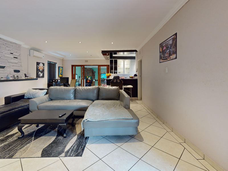 Open-plan living area featuring tiled flooring, a stone-clad fireplace, and integrated kitchen space with direct access to the outdoor area.
