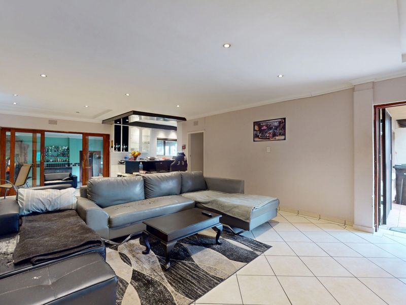 Spacious open-plan living area featuring tiled flooring, recessed lighting, and direct access to outdoor spaces through sliding glass doors.