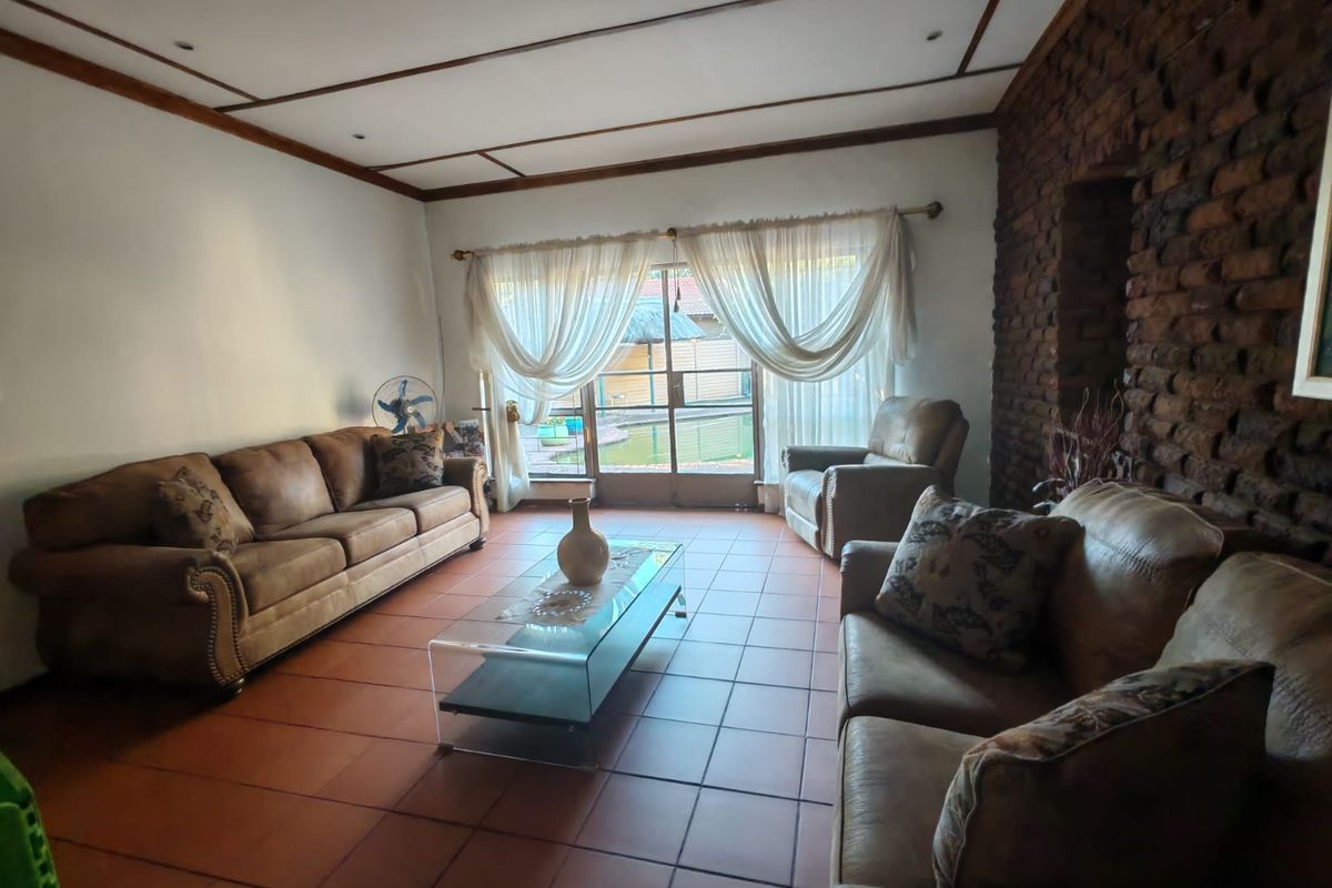 Spacious living room featuring an exposed brick feature wall, terracotta floor tiles, and sliding glass doors providing access to the outdoor area.