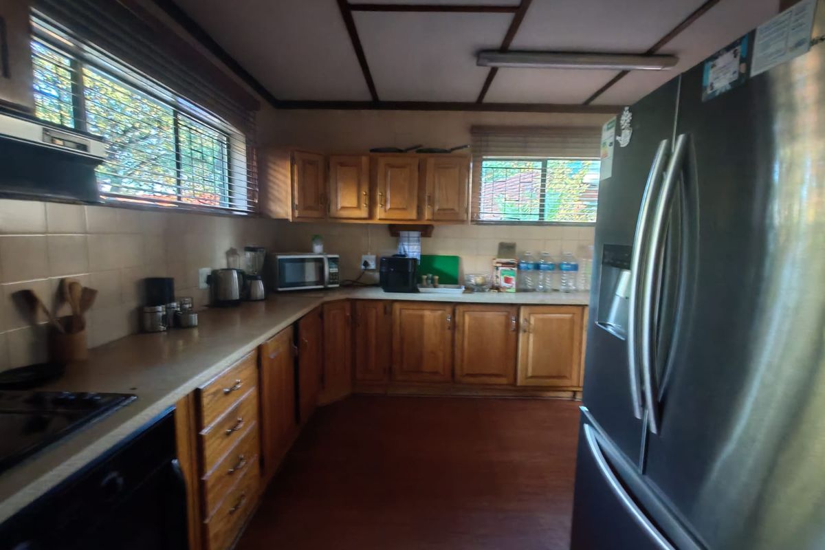 A functional kitchen featuring wooden cabinetry, laminate countertops, tiled backsplash, and built-in appliances, offering a traditional layout with ample storage space.