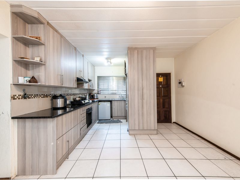 A functional kitchen featuring light wood-grain cabinetry, granite countertops, built-in oven, and tiled flooring, offering a clean and practical layout for daily use.