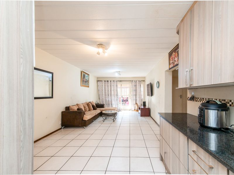Open-plan living area featuring tiled flooring, a functional kitchen with granite countertops, and direct access to an outdoor balcony through sliding glass doors.