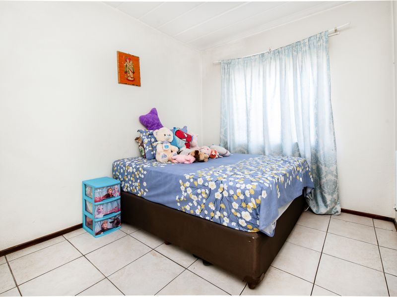 A functional bedroom featuring tiled flooring and a window with a curtain rail, providing a neutral base for personalization.