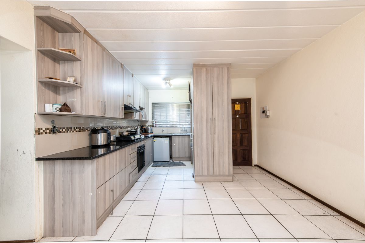 A functional kitchen featuring light wood-grain cabinetry, granite countertops, built-in oven, and tiled flooring, offering a clean and practical layout for daily use.