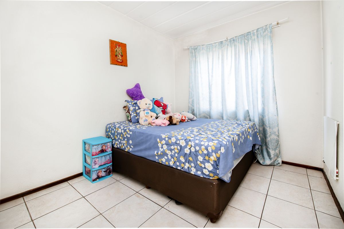 A functional bedroom featuring tiled flooring and a window with a curtain rail, providing a neutral base for personalization.