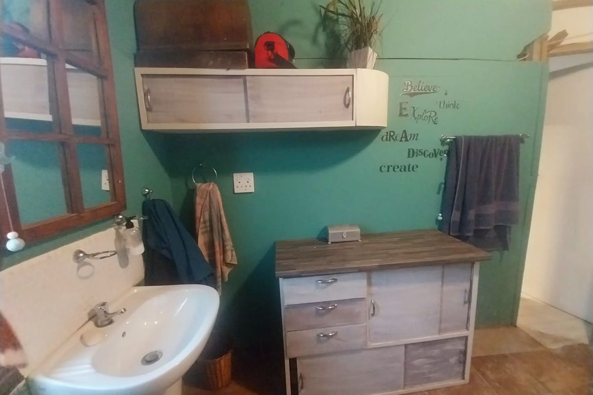 A bathroom featuring a pedestal basin, wall-mounted cabinetry, and a vanity unit with a wood-look countertop.