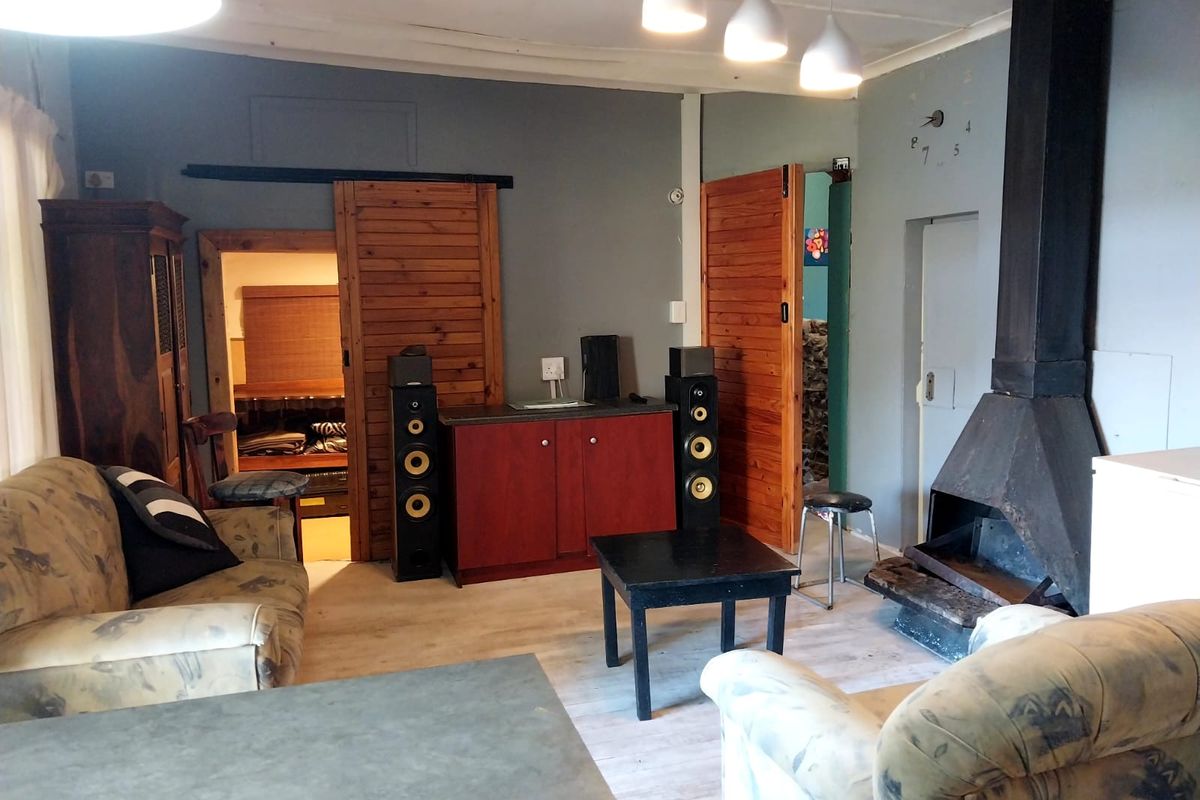 Living room featuring a built-in metal fireplace, wooden sliding doors, and light-toned flooring, offering a rustic aesthetic with potential for cosmetic updates.