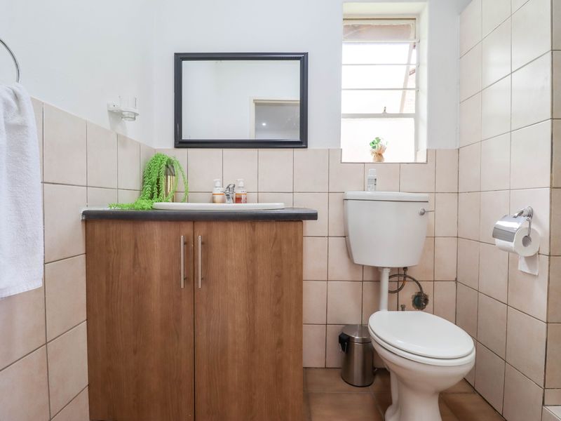 A functional bathroom featuring a vanity cabinet with a basin, a standard toilet, and neutral wall tiling.