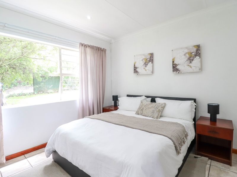 A bright and well-maintained bedroom featuring tiled flooring, a large window providing natural light, and coved ceiling finishes.