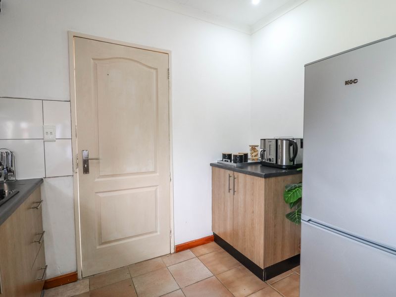 A functional kitchen area featuring wood-look cabinetry, dark laminate countertops, a gas hob, and tiled flooring.