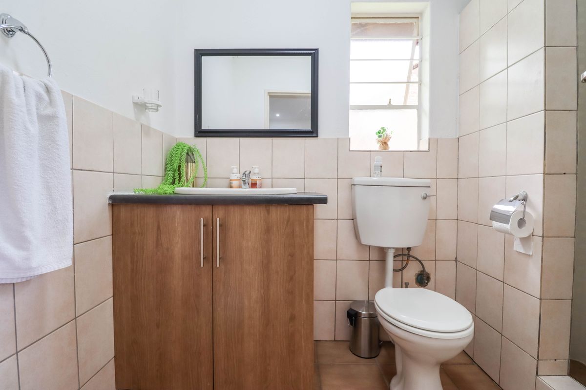 A functional bathroom featuring a vanity cabinet with a basin, a standard toilet, and neutral wall tiling.