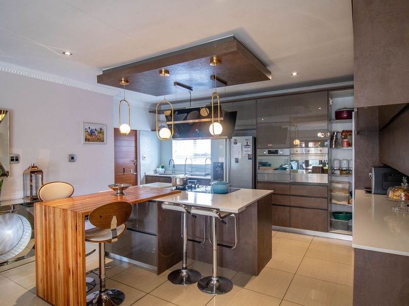 Modern kitchen featuring a central island with breakfast bar, high-end built-in appliances, sleek cabinetry, and contemporary pendant lighting.