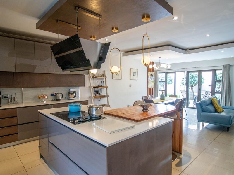 Modern open-plan kitchen and living area featuring a central island, sleek cabinetry, high-end finishes, and seamless access to the outdoor patio.