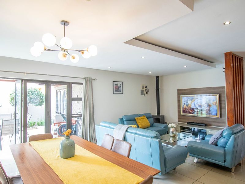 Spacious open-plan living and dining area featuring tiled floors, a modern fireplace, and large sliding doors providing seamless access to the outdoor patio.
