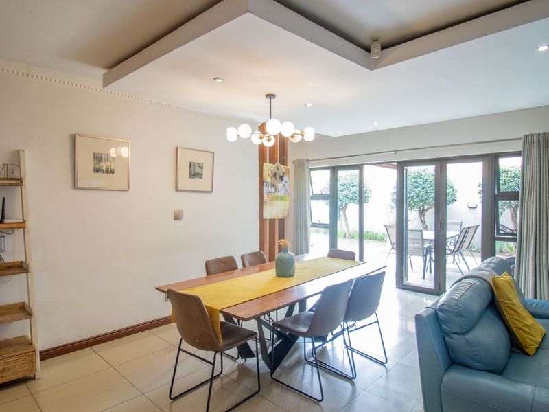 Open-plan living and dining area featuring tiled floors, recessed ceiling lighting, and large aluminium sliding doors providing direct access to the outdoor patio.