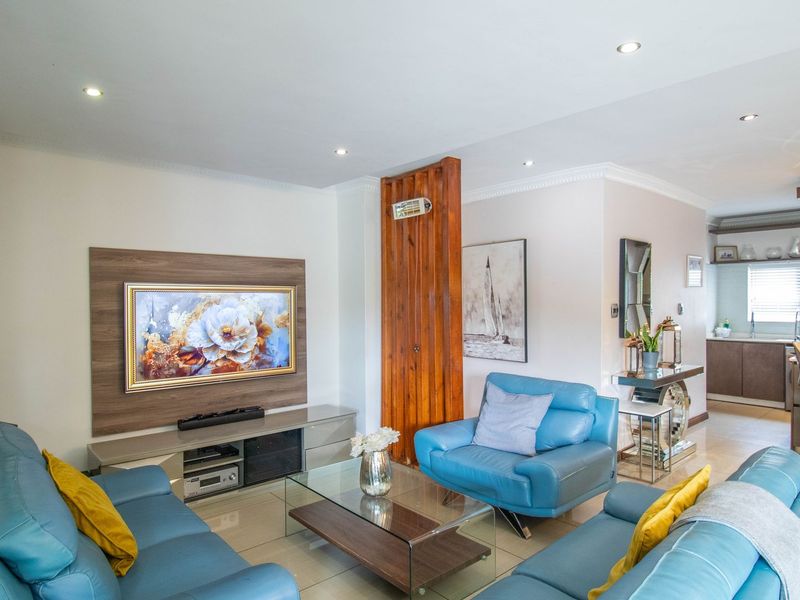 Open plan living area featuring a modern kitchen with island, tiled floors, recessed lighting, and a feature timber wall with a freestanding fireplace.