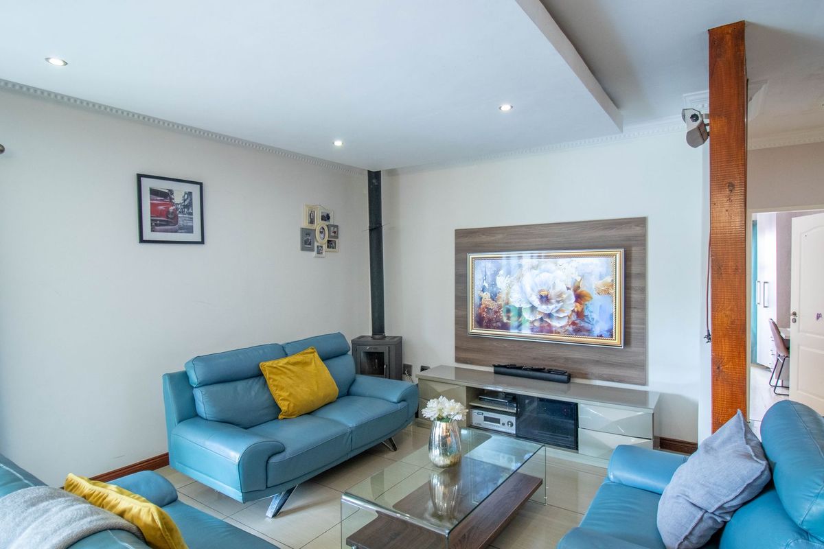 A well-maintained living room featuring a wood-burning fireplace, recessed ceiling with downlights, and a built-in media unit with tiled flooring.