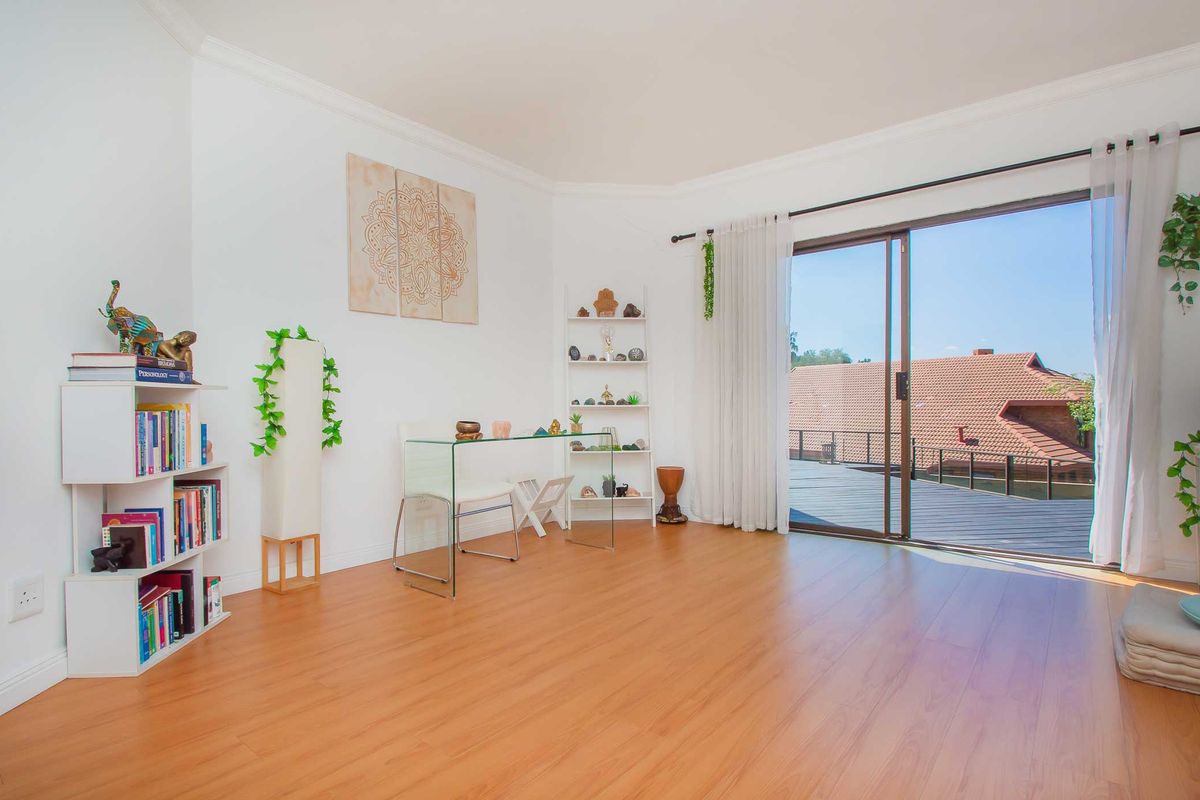 Bright bedroom featuring laminate flooring, crown molding, and large sliding glass doors providing access to an outdoor deck area.