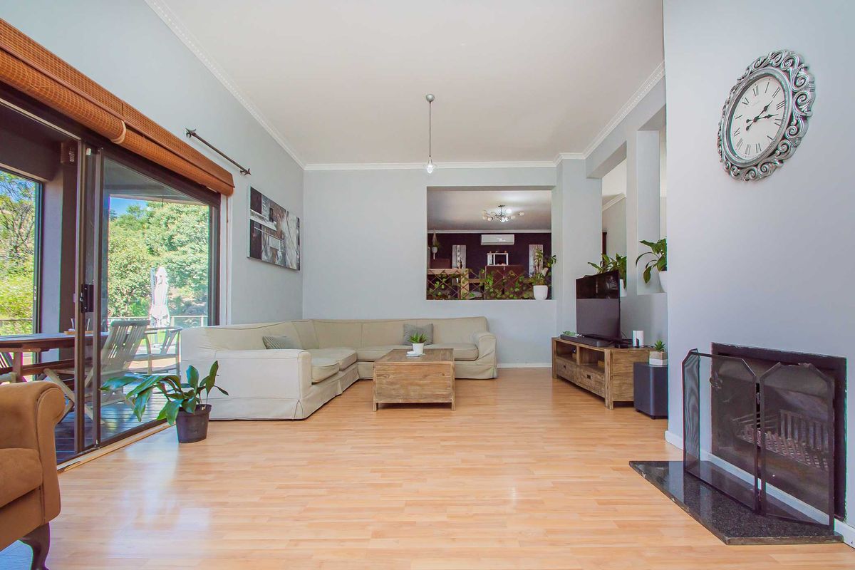 Spacious living room featuring light wood laminate flooring, a built-in fireplace with a stone hearth, and large sliding glass doors leading to the patio.